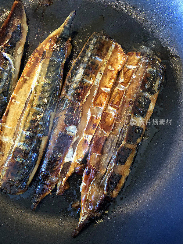 早餐在厨房灶具上不粘锅中煎炸鲭鱼片，干煎并食用健康的鱼油- 5天然补充鲭鱼和鲑鱼片，脆皮和天然鱼油，家庭烹饪。